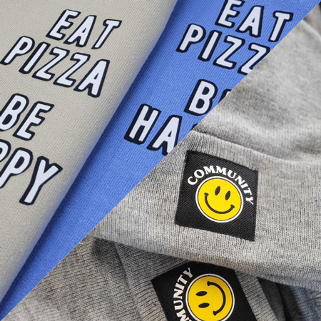 Pile of vinyl printed clothing, Eat Pizza Be Happy and Community Gym smiley graphic.