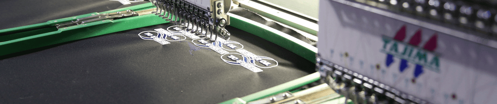 Embroidery machine making small white graphics on black paper.
