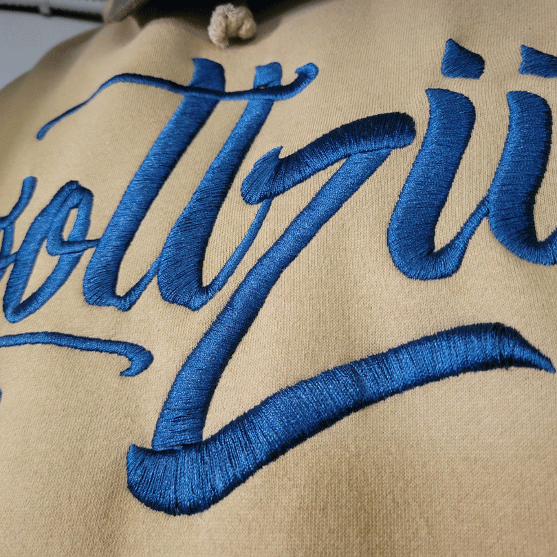 Gottzu in blue embroidery on beige hoodie.