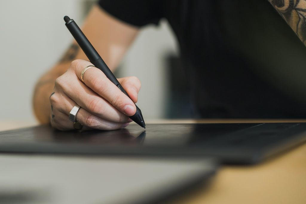 Person using digital tablet and stylus to write or draw something.