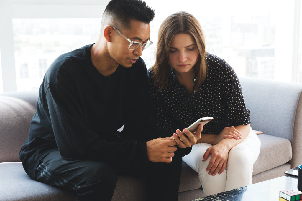 Women and man on couch looking at mobile phone.